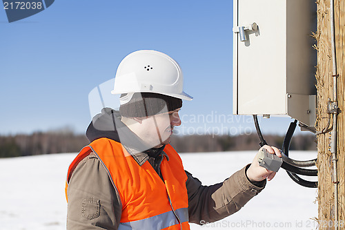 Image of Electrician with electrical cable in the hands near switchboard