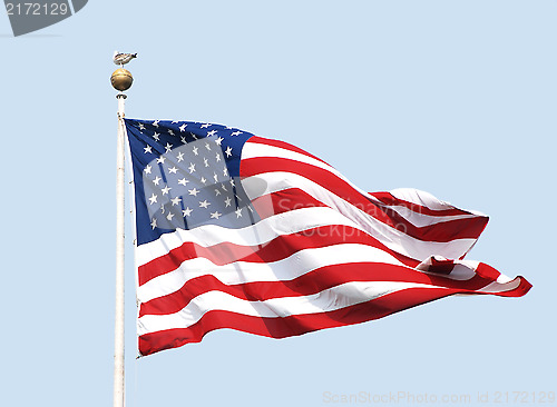 Image of The American flag flies on a sunny day against a clear blue sky.