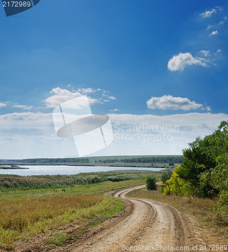 Image of rural road near river under cloudy sky