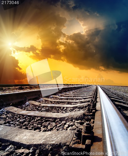 Image of railway to horizon under dramatic sky with sun