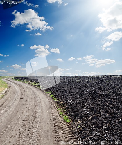 Image of rural road near black ploughed field