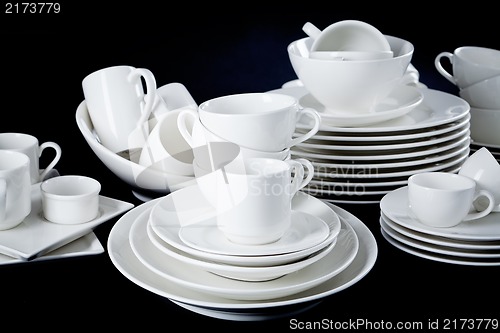 Image of mixed white dishes cups and plates isolated on black