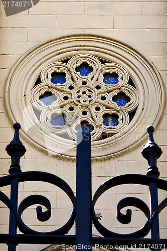 Image of  colored rose window and a iron grate 