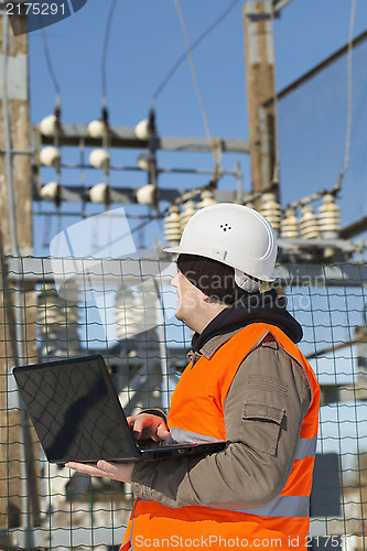 Image of Electrician with computer near the electricity substation