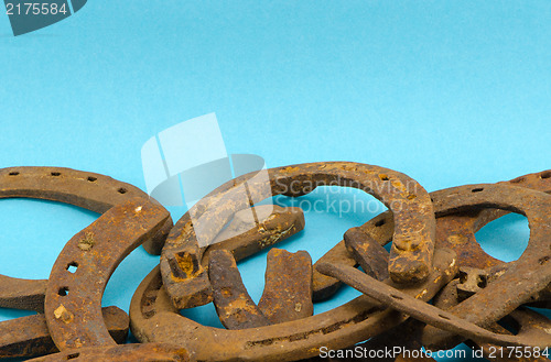 Image of stack old retro rusty horseshoe blue background 