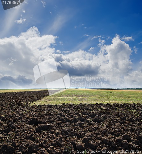 Image of black ploughed field under cloudy sky