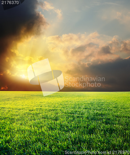 Image of sunset in dramatic sky over green field