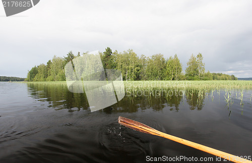 Image of wooden paddle with water drops against summer lake