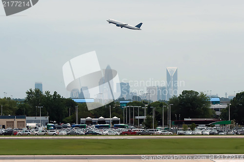 Image of Commercial jet in the air with city skyline in the background.