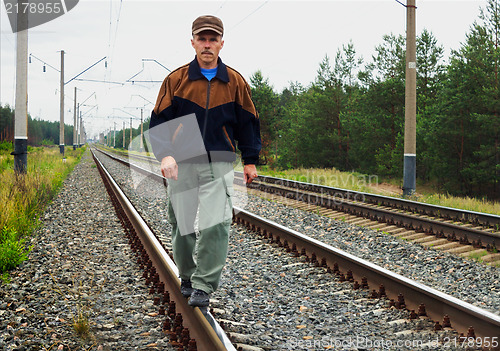 Image of An elderly man walking on tracks