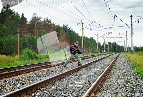 Image of An elderly man crosses a railway embankment