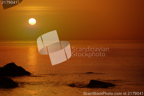 Image of Orange sunset over the sea with rocks