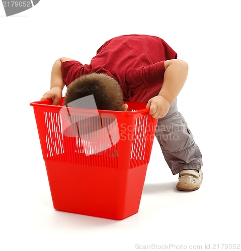 Image of Little boy looking deep into garbage bin