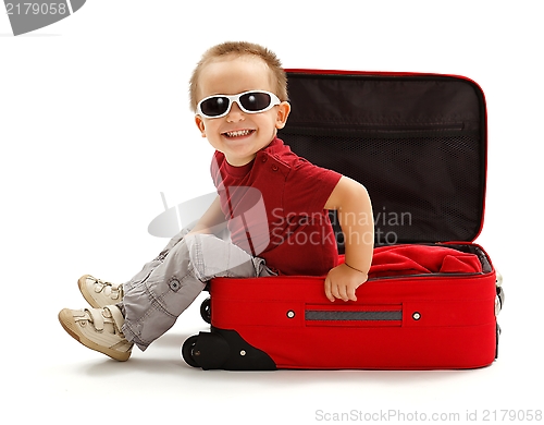 Image of Playful little boy with sunglasses, sitting in suitcase