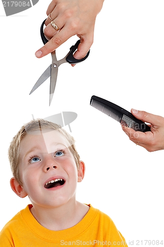 Image of Scared little boy looking up to scissor and comb