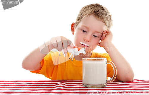 Image of Young kid playing with toy cow behind glass of milk