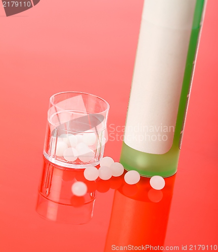 Image of Homeopathic pills and container on red