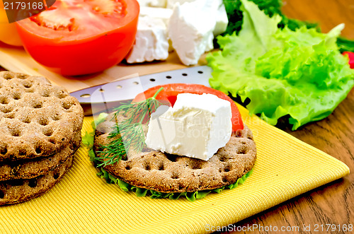 Image of Feta cheese and tomato on a round bread with a knife