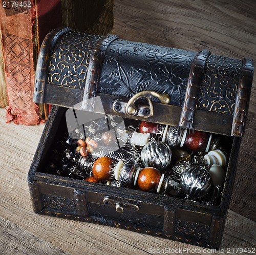 Image of  casket with jewelry and old book on a wooden surface 