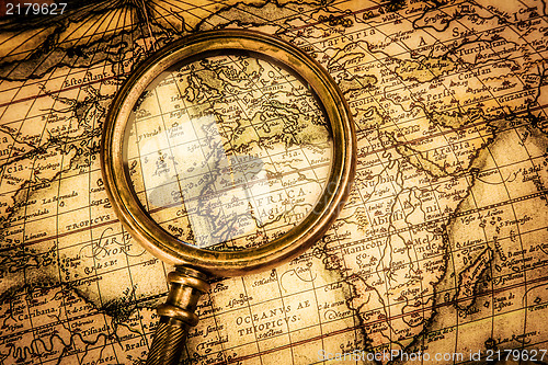 Image of Vintage magnifying glass lies on an ancient world map