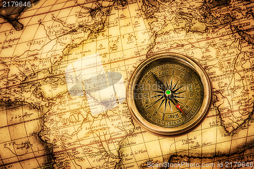 Image of Vintage compass lies on an ancient world map.