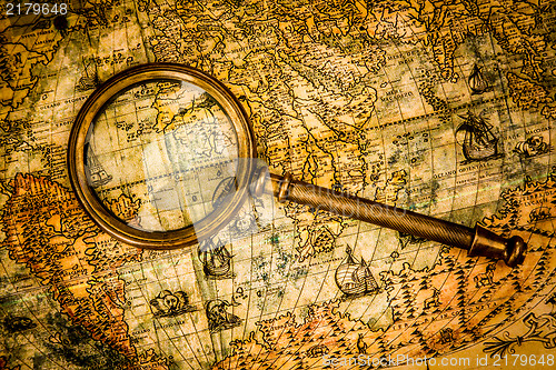 Image of Vintage magnifying glass lies on an ancient world map