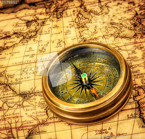 Image of Vintage compass lies on an ancient world map.