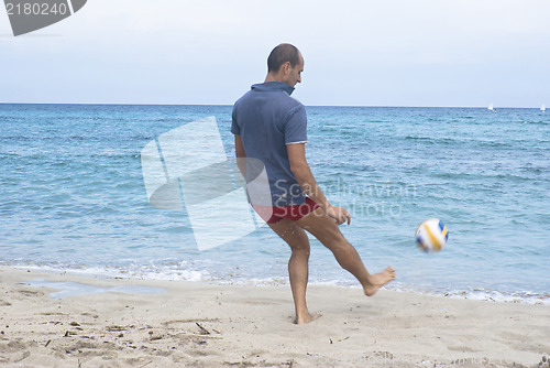 Image of Man on the beach playing soccer 