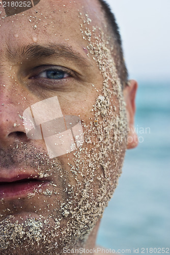 Image of half face covered with sand