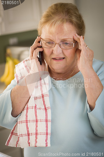 Image of Shocked Senior Adult Woman on Cell Phone in Kitchen