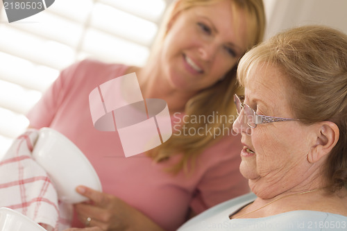 Image of Senior Adult Woman and Young Daughter Talking in Kitchen