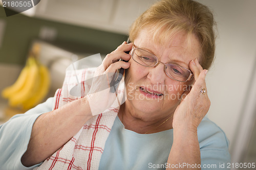 Image of Shocked Senior Adult Woman on Cell Phone in Kitchen