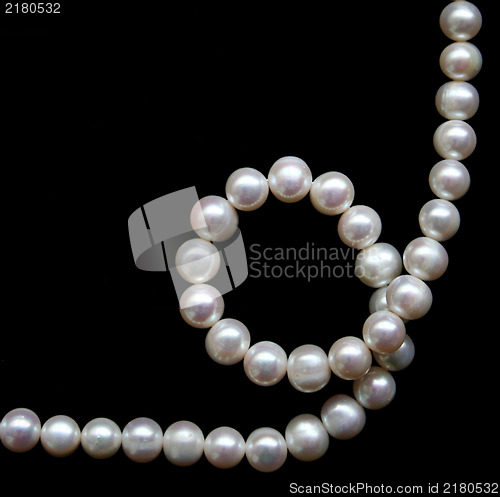 Image of White pearls on the black silk as background 