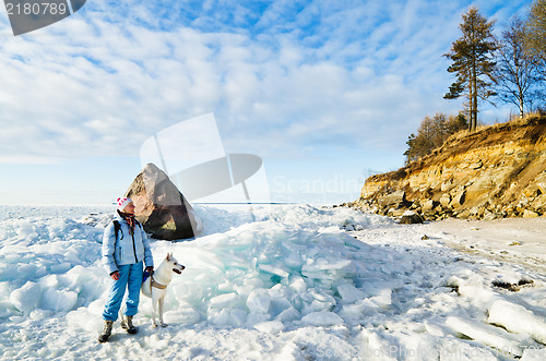 Image of Woman with a dog walk on a sunny winter day on the coast of the 