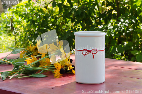 Image of rudbekia flowers lie wooden table near white vase 