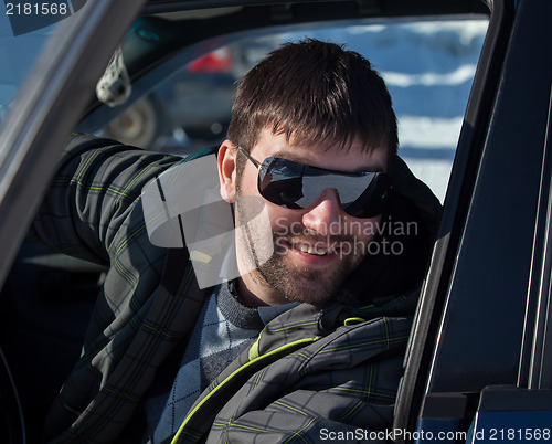 Image of A young man wearing sunglasses in a private car