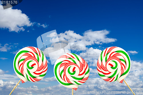 Image of Three sugar lollipops in white green and red on background of sk