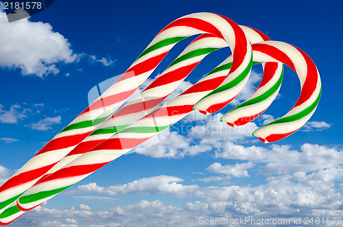 Image of Three sugar sticks in white green and red on background sky and 