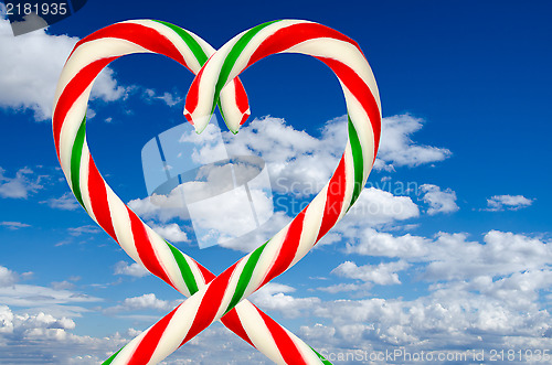 Image of Heart of sugar sticks on background of sky and clouds