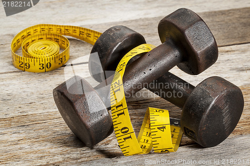 Image of iron dumbbells and measuring tape