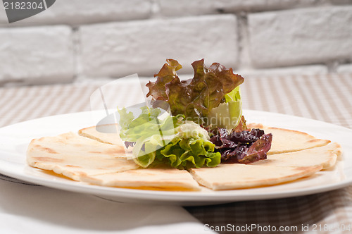 Image of garlic pita bread pizza with salad on top