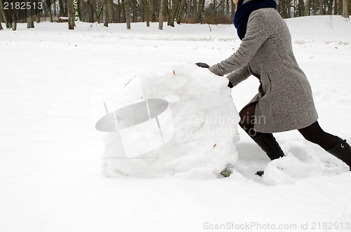 Image of woman grey coat push big snow roll winter meadow 