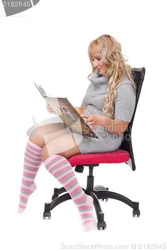 Image of young girl reading book sitting on a chair in a bright room. Iso