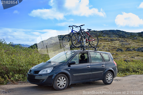 Image of two bicycles mounted on roof of car against sky