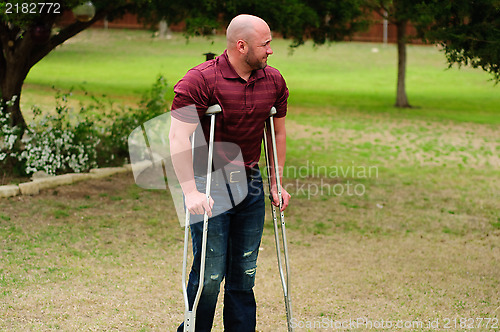 Image of Muscular bald man on crutches