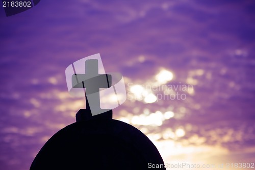 Image of Silhouette of a church top with a cross a sunset in background