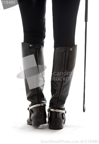 Image of beautiful legs in black leather horseman boots with riding-crop