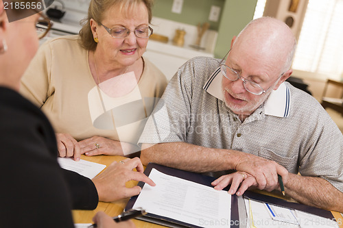 Image of Senior Adult Couple Going Over Papers in Their Home with Agent
