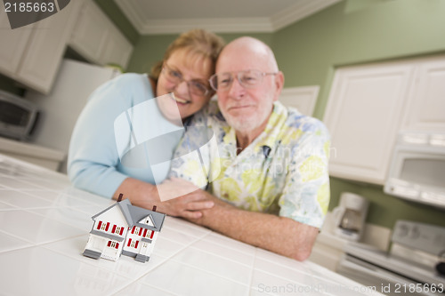 Image of Senior Adult Couple Gazing Over Small Model Home on Counter