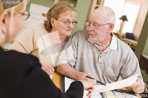 Image of Senior Adult Couple Going Over Papers in Their Home with Agent